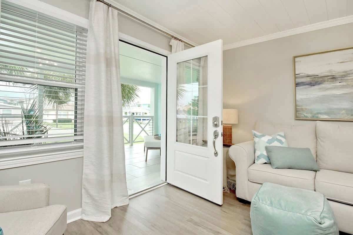 A room with a sliding glass door leading to an outdoor area, a sofa with cushions, and a painting on the wall.