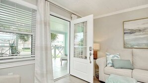 Una habitación con puerta corrediza de vidrio que da a un espacio exterior, un sofá con cojines y un cuadro en la pared.