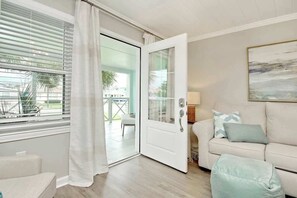 Ein Zimmer mit einer Schiebetür zum Außenbereich, einer Couch mit Kissen und einem Bild an der Wand.