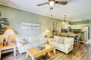 Ein Wohnzimmer mit einem weißen Sofa, einem Holztisch und einem Deckenventilator.