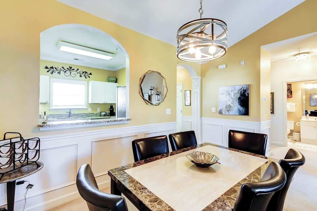 Un espace repas avec une table en marbre, des chaises noires et un lustre.