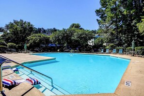A swimming pool with lounge chairs and umbrellas, surrounded by trees. - Golf Retreat Unit 832 (North Myrtle Beach)