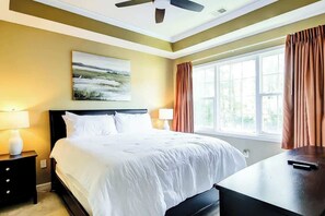 A hotel room with a bed, bedside lamps, a painting, a window with curtains, and a ceiling fan. - Golf Retreat Unit 832 (North Myrtle Beach)