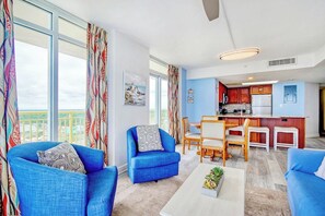 Un salon avec des canapés bleus, une table basse et une vue sur la cuisine.