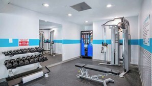 A gym with weightlifting equipment, benches, and a Powerade refrigerator. - Bay Watch Resort 1740 (North Myrtle Beach)