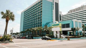 A hotel with a modern design, featuring a prominent 'Landmark' sign, multiple floors, and a parking area with several cars. - Landmark Resort 1208 (Myrtle Beach)