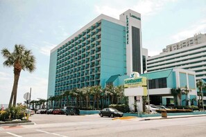 A hotel with a modern design, featuring a prominent 'Landmark' sign, multiple floors, and a parking area with several cars. - Landmark Resort 1208 (Myrtle Beach)