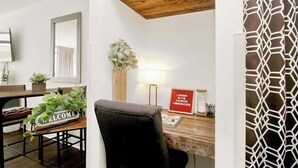 A room with a wooden desk, a chair, a welcome sign, a plant, a lamp, and a framed sign with text. - Landmark Resort 1208 (Myrtle Beach)
