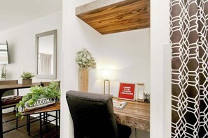A room with a wooden desk, a chair, a welcome sign, a plant, a lamp, and a framed sign with text. - Landmark Resort 1208 (Myrtle Beach)