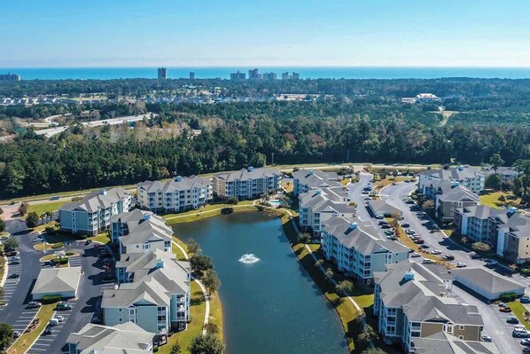 A residential area with apartment buildings, a body of water, and a distant cityscape. - Luster Leaf Unit 201 (Myrtle Beach)