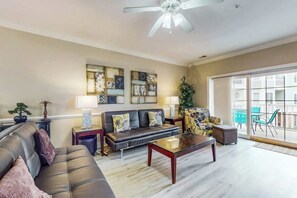 A living room with a sofa, coffee table, and artwork on the wall. - Luster Leaf Unit 201 (Myrtle Beach)