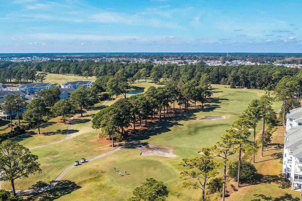 Un terrain de golf avec un club-house et des immeubles résidentiels en arrière-plan.