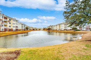 A residential area with multi-story buildings, a central water feature, and a clear sky. - Luster Leaf Unit 201 (Myrtle Beach)