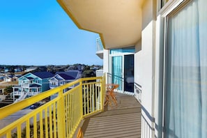 A balcony with a yellow railing, a small table, and a view of houses in the distance. - Bay Watch Resort 0640 (North Myrtle Beach)