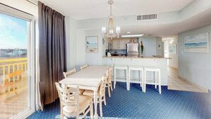 Quarto de hotel com área de jantar, cozinha compacta e uma grande janela com vista.
