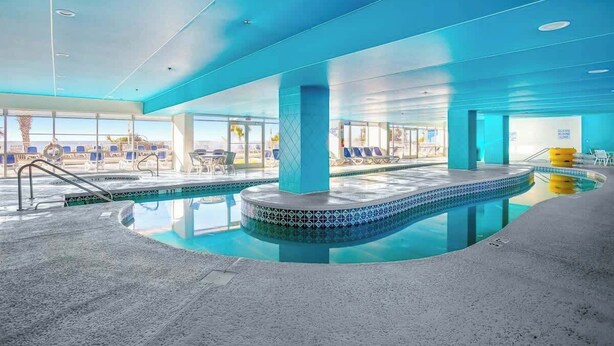 Uma área de piscina com design circular, paredes de vidro transparente e vista para o exterior.
