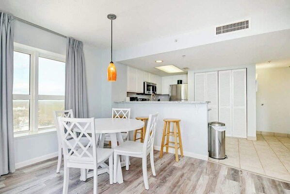 A modern kitchen with white cabinets, a microwave, and a stainless steel sink.