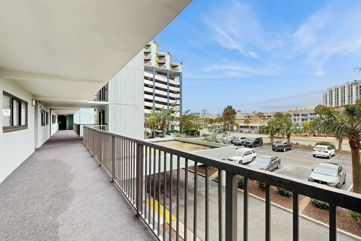 A balcony with a view of a parking lot and adjacent buildings.
