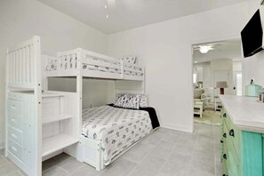 Un llit amb lliteres i calaixos d'emmagatzematge, un televisor fixat a la paret i una zona de cuina amb armaris.