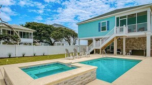 A backyard with a swimming pool, a covered patio, and a two-story house. - Grace by the Sea Retreat (Atlantic Beach)