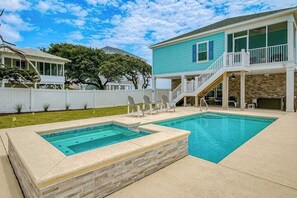 A backyard with a swimming pool, a covered patio, and a two-story house. - Grace by the Sea Retreat (Atlantic Beach)