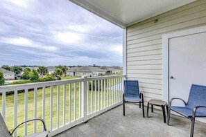 A balcony with a white railing, two blue chairs, and a small table. - The Perfect Getaway at Wickham Dr (Myrtle Beach)