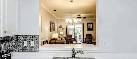 A kitchen with a double sink, a coffee maker, and a patterned backsplash.