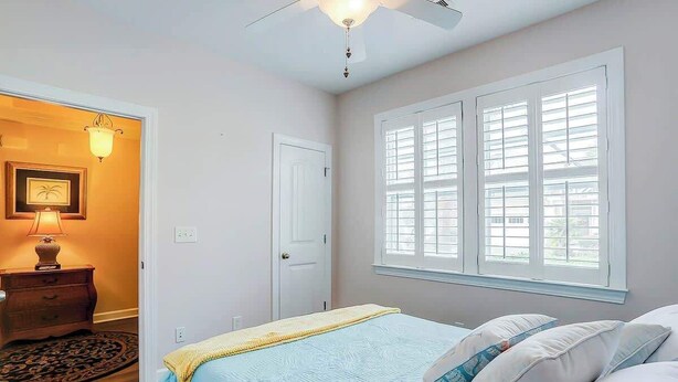A bedroom with a bed, a nightstand, a lamp, a door, and a window with blinds. - Clearwater Bay Unit 1012 (North Myrtle Beach)