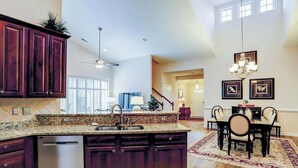 A spacious kitchen with dark cabinetry, a granite countertop, and a built-in dishwasher. - Clearwater Bay Unit 1012 (North Myrtle Beach)