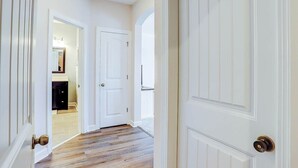 A hallway with white doors and wooden flooring. - Clearwater Bay Unit 1012 (North Myrtle Beach)