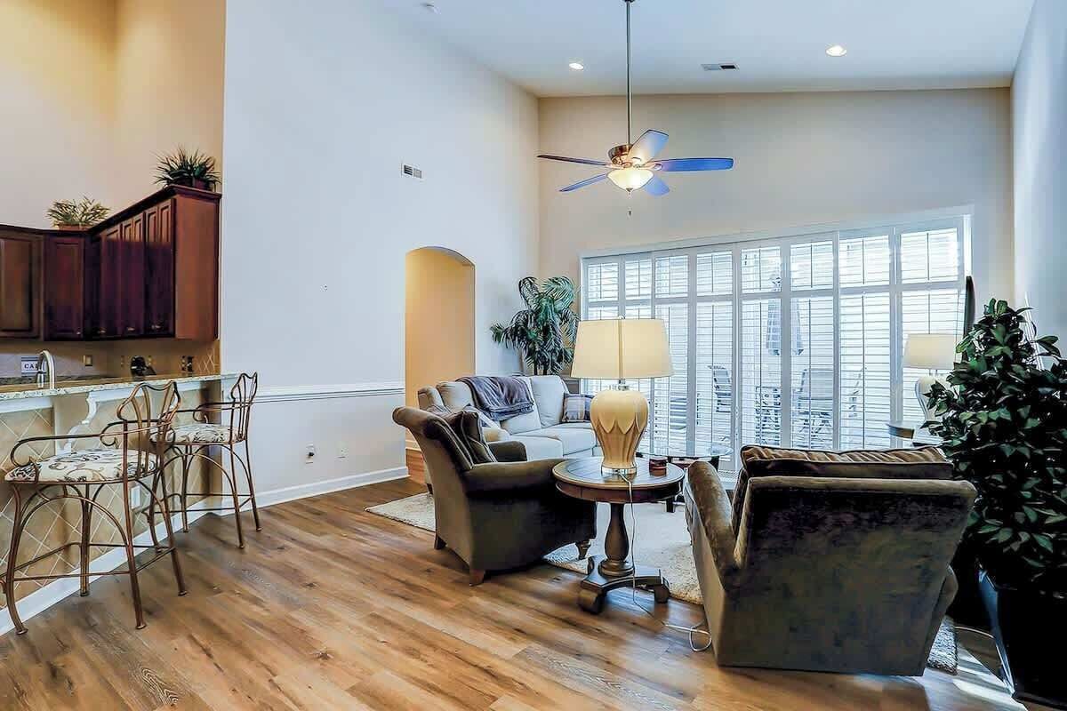 A spacious living area with a dining table, chairs, a sofa, and a ceiling fan.