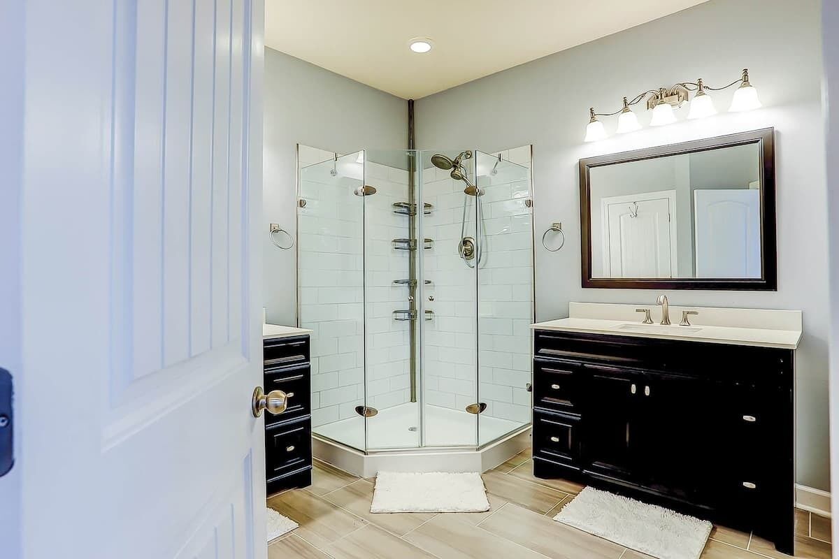 A modern bathroom with a glass-enclosed shower, a large mirror, and black cabinetry.