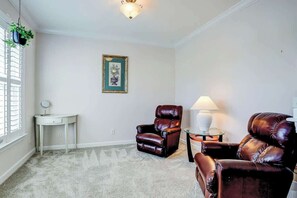 A room with a carpeted floor, a framed picture on the wall, a desk with a lamp, and two leather chairs. - Clearwater Bay Unit 1012 (North Myrtle Beach)