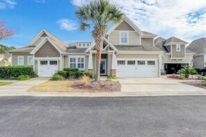 A residential house with a garage, a driveway, and a palm tree. - Clearwater Bay Unit 1012 (North Myrtle Beach)