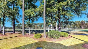 A park with trees, a grassy area, and a fence. - Paradise on the Course 303 (Myrtle Beach)