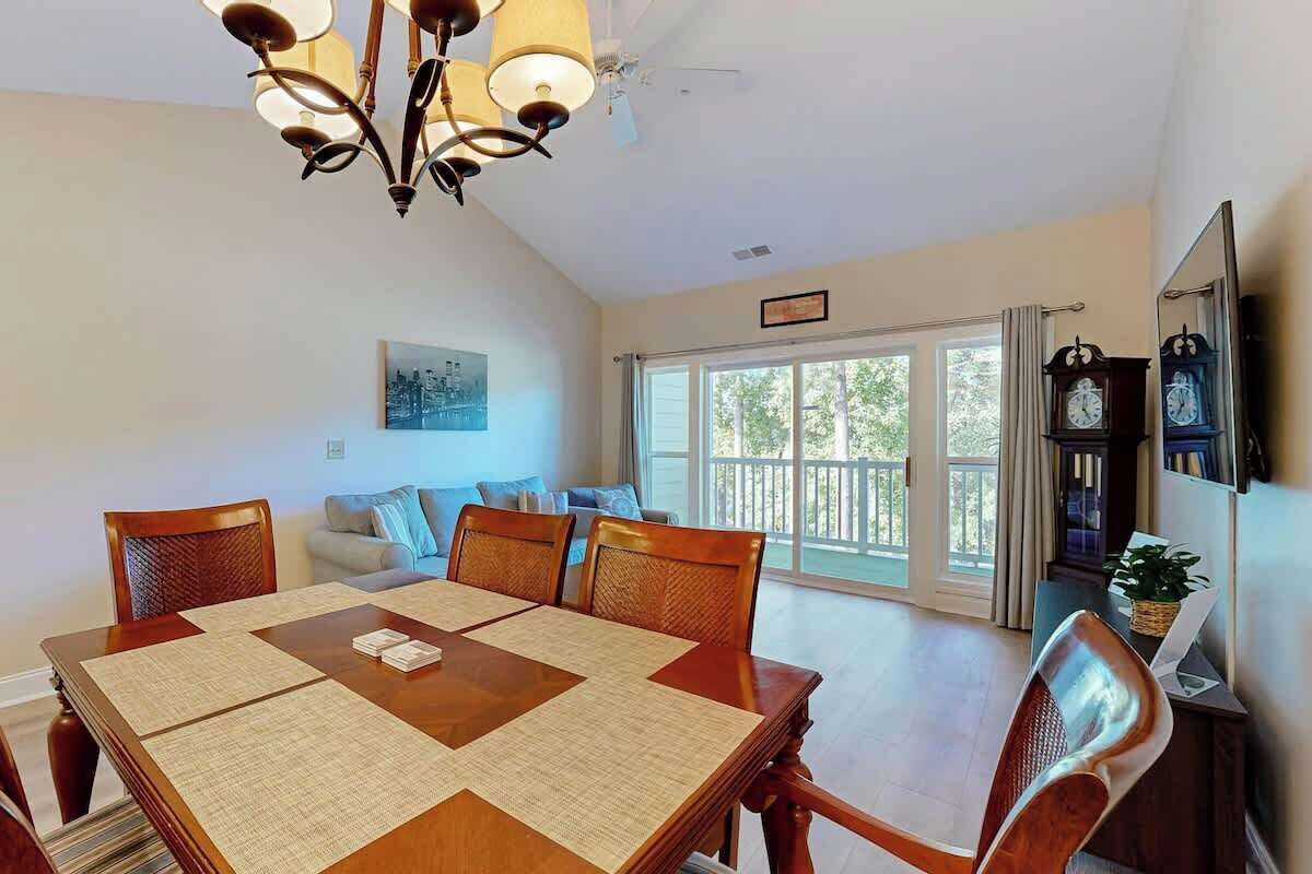 A dining area with a wooden table, chairs, and a chandelier.
