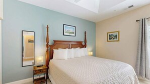 A hotel room with a large bed, a bedside table with a lamp, a ceiling fan, and two framed pictures on the walls. - Paradise on the Course 303 (Myrtle Beach)