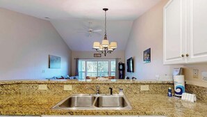 A kitchen with granite countertops, stainless steel sinks, and white cabinetry. - Paradise on the Course 303 (Myrtle Beach)