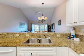A kitchen with granite countertops, stainless steel sinks, and white cabinetry. - Paradise on the Course 303 (Myrtle Beach)