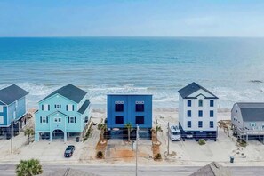 Um imóvel à beira-mar com três casas, uma área de estacionamento e vista para o oceano.