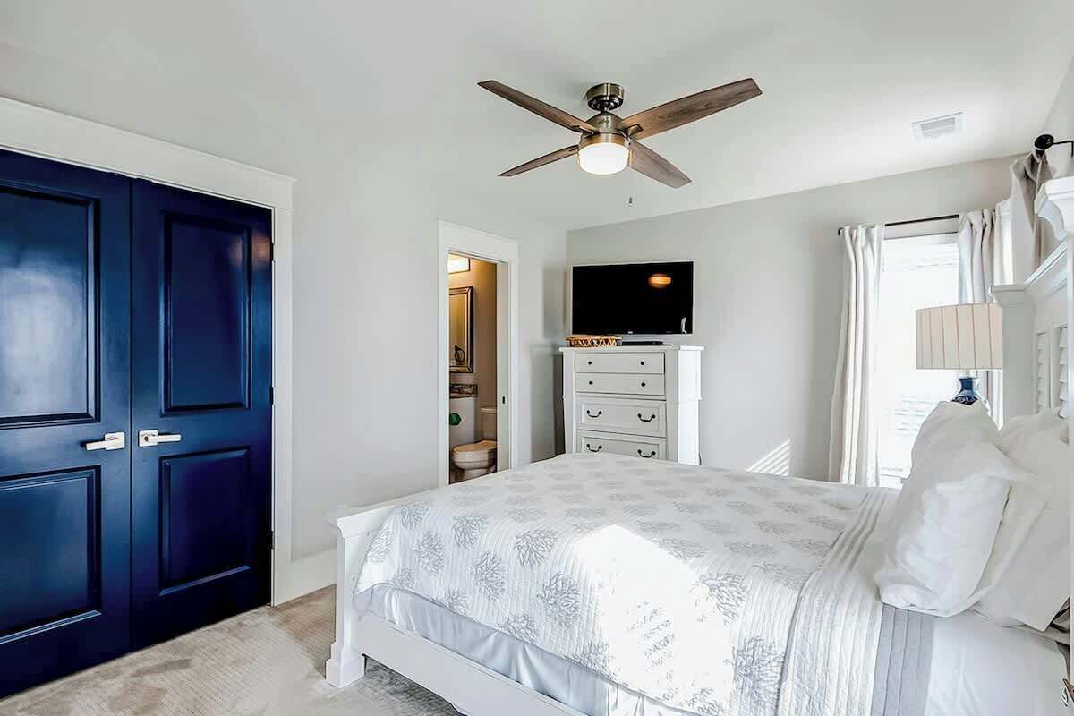 A bedroom with a bed, a ceiling fan, a television, and a wardrobe.