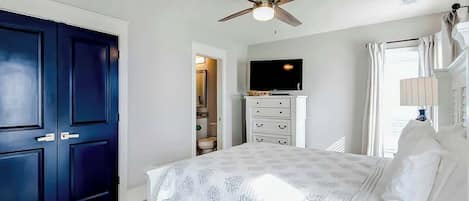 A bedroom with a bed, a ceiling fan, a television, and a wardrobe.