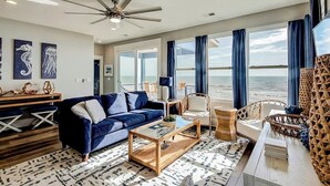 A spacious living area with a blue sofa, a coffee table, and a ceiling fan. - Blue Wave Beach Retreat (Murrells Inlet)
