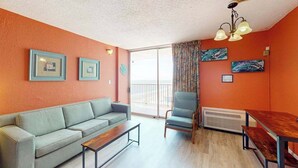 A living room with a sofa, a chair, a table, and artwork on the walls. - Sands Ocean Club 1101 Fruit Cakes (Myrtle Beach)