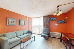 A living room with a sofa, a chair, a table, and artwork on the walls. - Sands Ocean Club 1101 Fruit Cakes (Myrtle Beach)