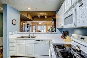 A kitchen with white cabinets, a dishwasher, a stove, and a microwave. - Tidewater 4214 Condo (North Myrtle Beach)
