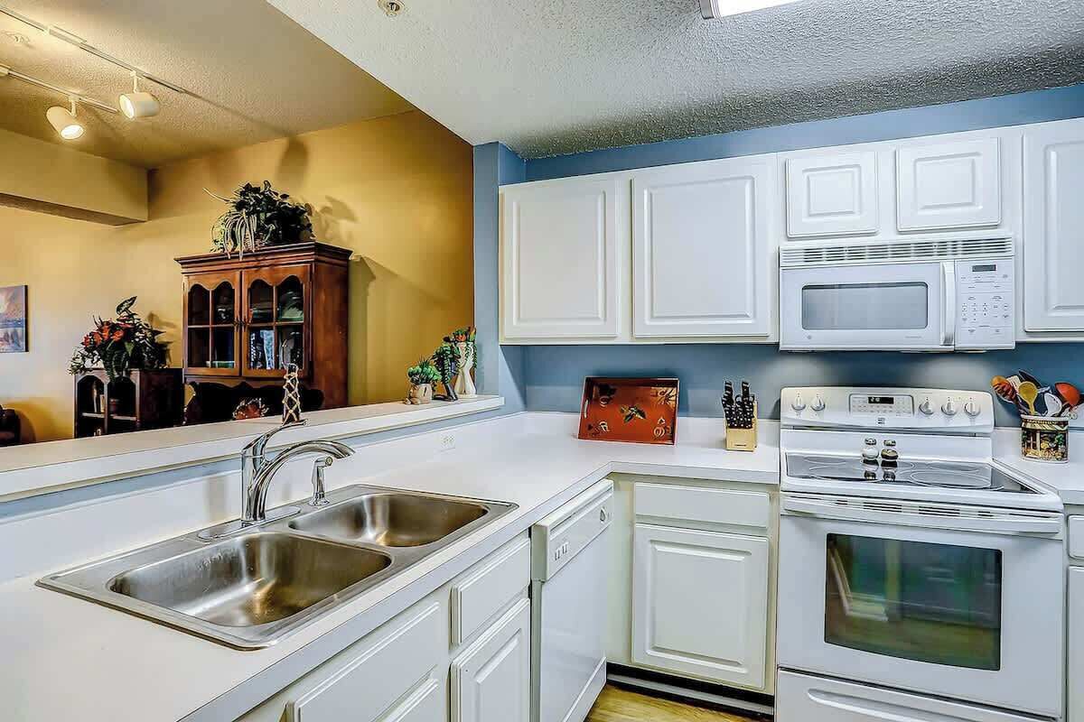 Una cocina moderna con armarios blancos, un lavamanos doble, un microondas y un horno.
