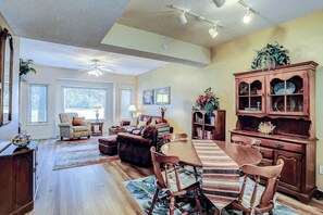 A spacious living room with a dining area, large windows, and a ceiling fan. - Tidewater 4214 Condo (North Myrtle Beach)