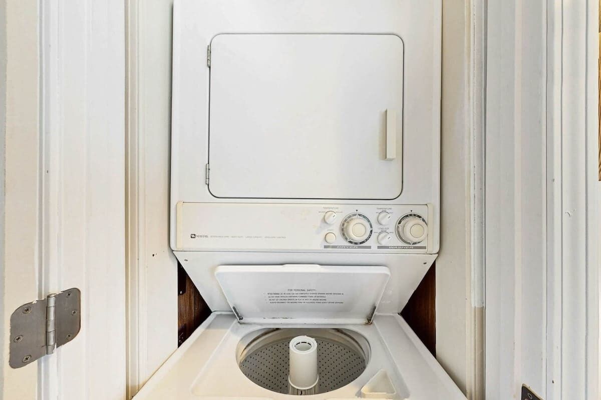 Een witte, compacte wasmachine met voorlader, bedieningspaneel en een deur aan de voorkant.