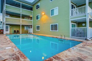A swimming pool with a stone deck, surrounded by a multi-story building with balconies. - Cherry Grove Pelican's Watch (North Myrtle Beach)
